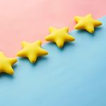 Yellow stars on pink and blue pastel background for rating or review concept.
